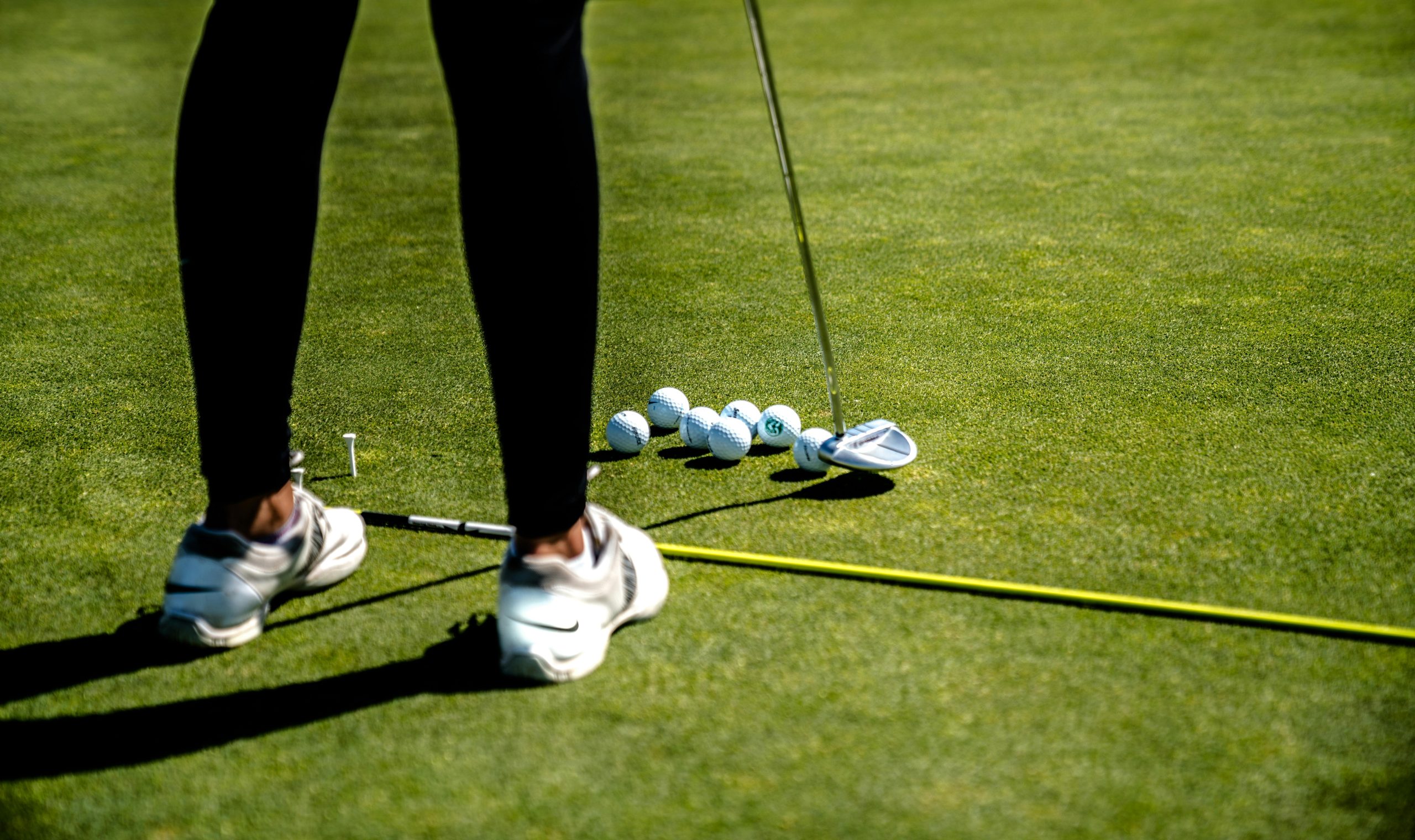 Golfer practicing with alignment sticks and golf balls on grass to improve swing path and fix a slice
