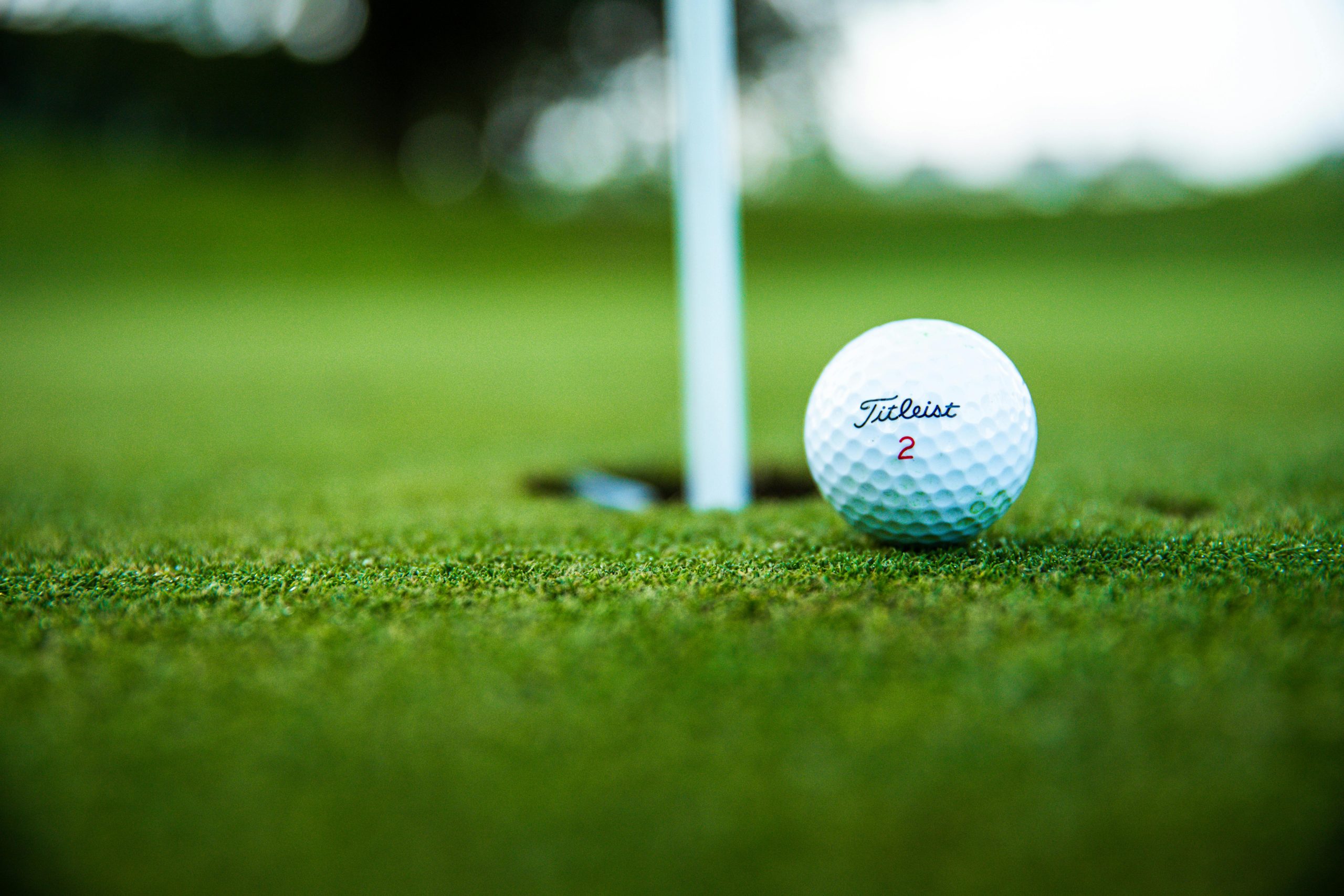 Close-up of a golf ball on the green near the hole, representing equipment choices that can influence ball flight and spin