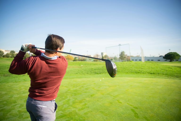 Golfer finishing a driver swing on a fairway, viewed from behind, suitable for illustrating ball flight direction in a push slice shot