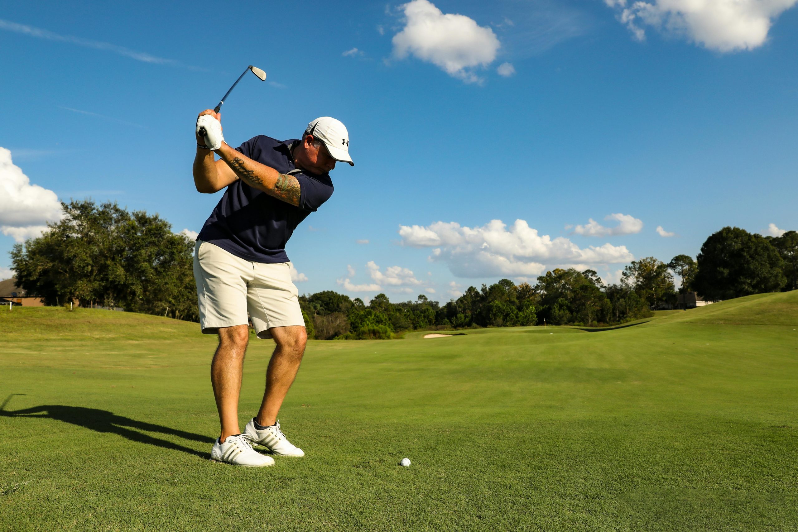 Golfer mid downswing hitting an iron shot on a fairway with ball positioned ahead, illustrating typical setup for iron strike
