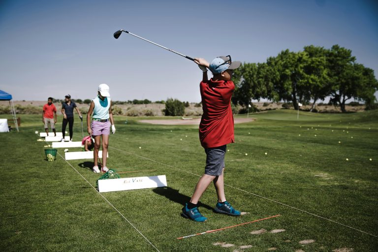 Golfer practicing with alignment sticks on the ground to improve swing path and fix a slice on a driving range