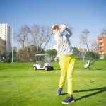 Golfer mid-swing on a course during a full follow-through, representing maintaining control and consistency under pressure